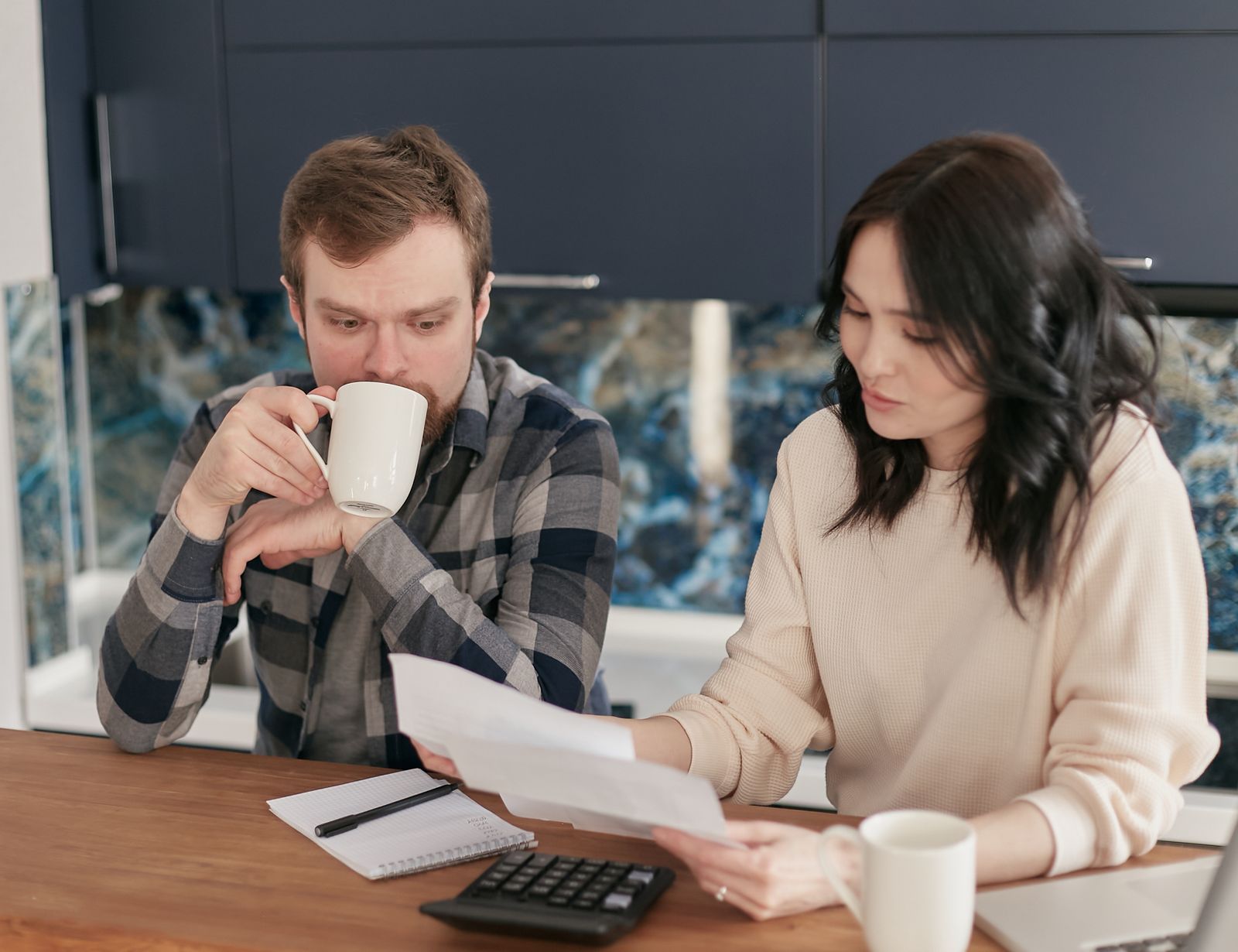 Pareja revisando facturas, deudas y presupuesto con una calculadora