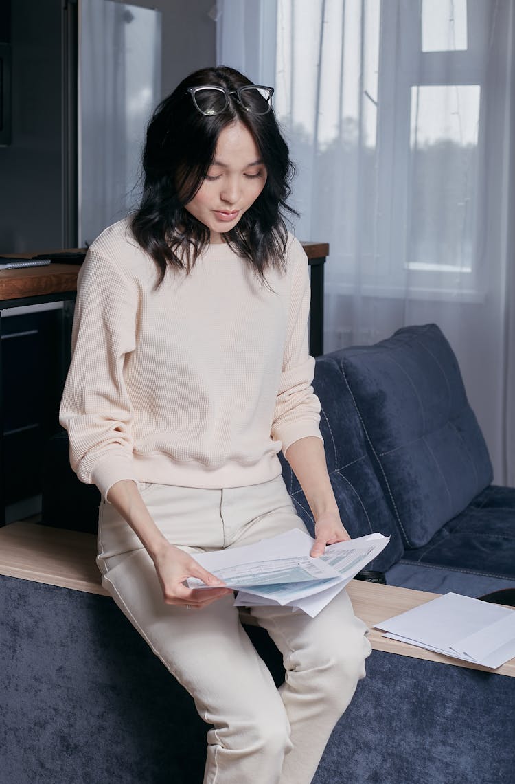 A Woman Sitting While Looking At Sheets Of Paper