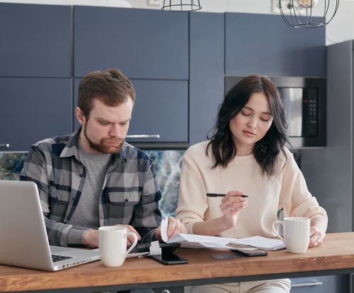 Free A man and woman working together at a kitchen table with laptops and documents. Stock Photo