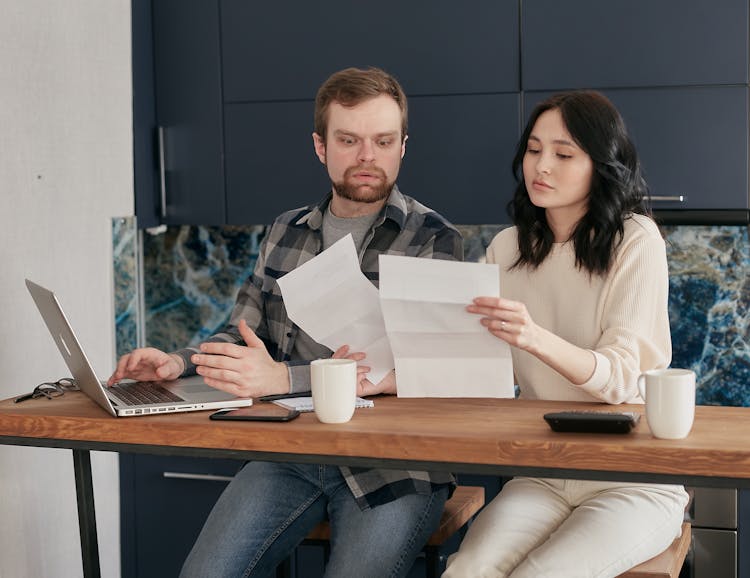 A Woman Holding Papers Sitting Beside A Shocked Man