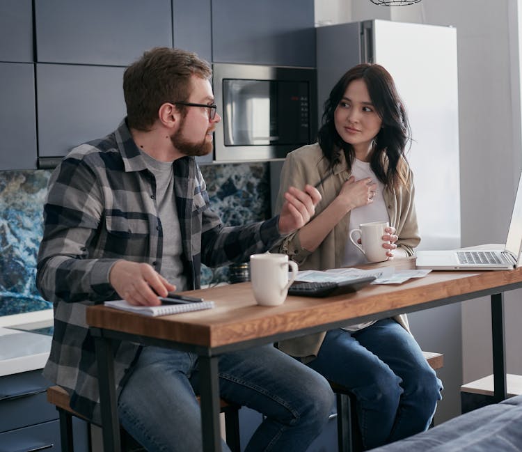 A Shocked Woman Holding A Cup Of Coffee Sitting Beside A Man 