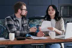 A couple reviews financial documents together at home, focusing on budgeting and bills.