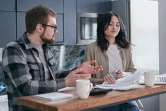 A couple reviewing financial documents in their kitchen, appearing focused and concerned.