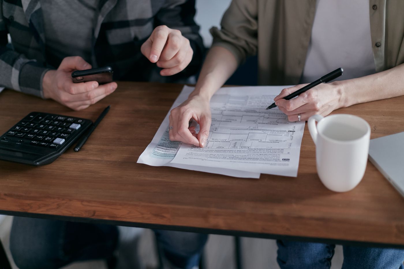 Personas revisando facturas, deudas y pagos atrasados con calculadora y documentos