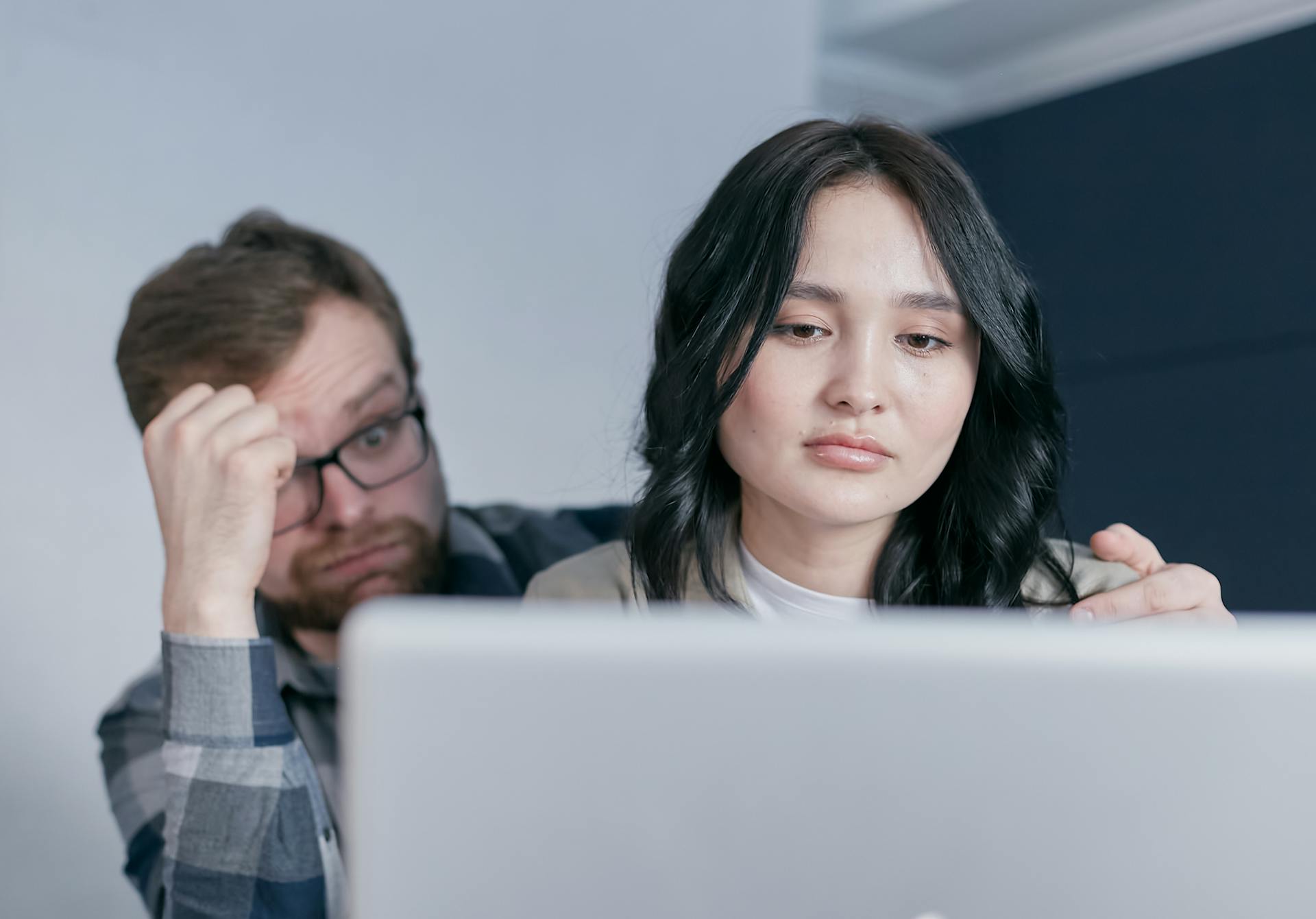 An interracial couple looking worried while checking finances at home.