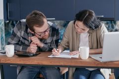 Couple reviewing financial documents together at a kitchen table with a laptop and calculator.