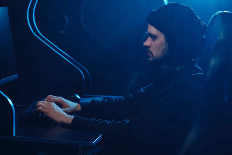 A Man With Headphones Typing On A Keyboard