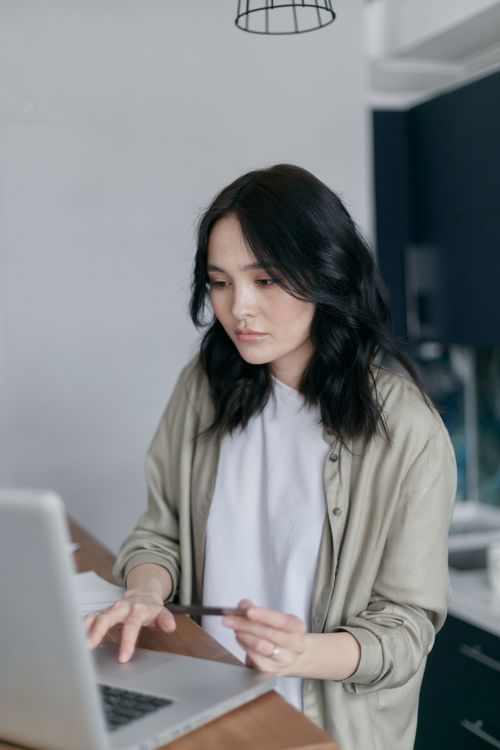 Free Asian woman shopping online with credit card in a cozy living room setting. Casual and modern lifestyle. Stock Photo