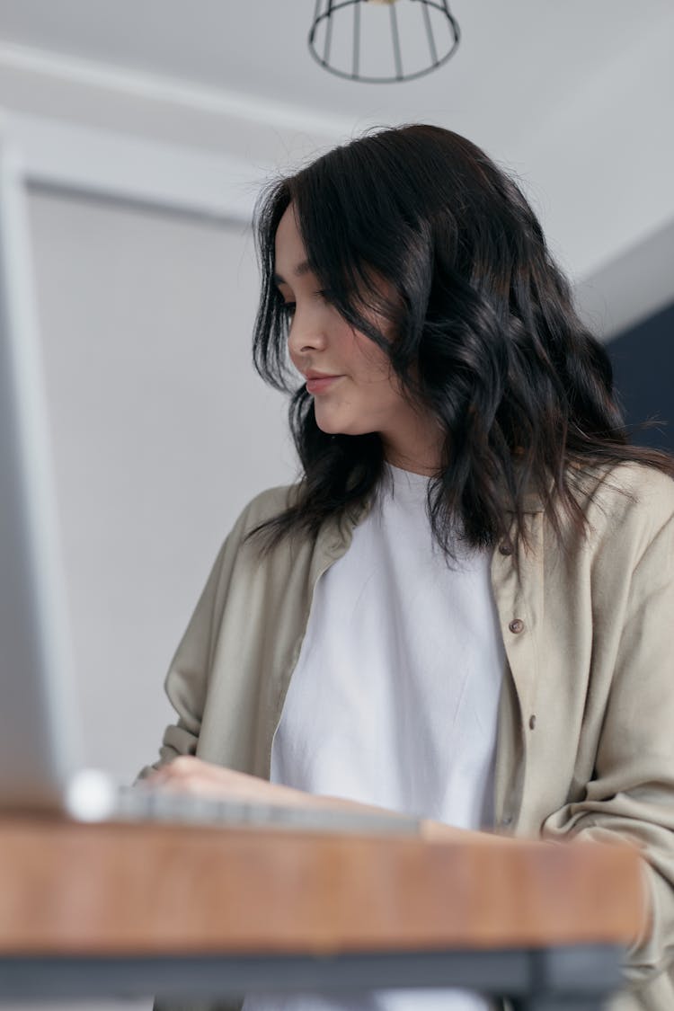 A Woman In Beige Cardigan Sitting Behind A Desk