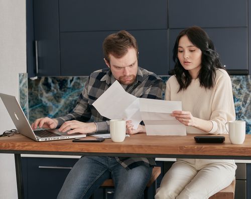 Free Two colleagues working on documents at a wooden table using a laptop indoors. Stock Photo