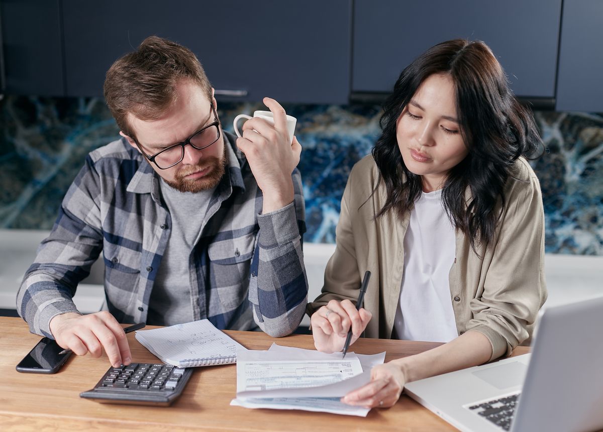 A member filling out a direct deposit form with a laptop and paperwork at home