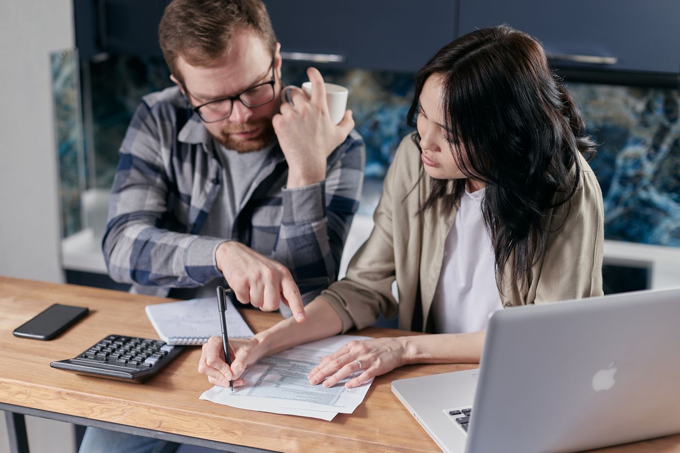 People reviewing bills and household finances with a calculator and laptop