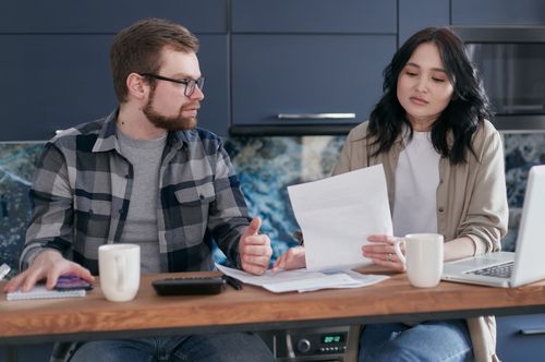 Free A couple sits at a table reviewing financial documents, looking concerned and focused. Stock Photo