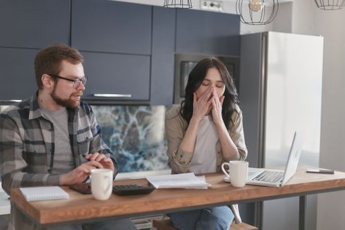 Free Two colleagues in an office discuss work, showing tired expressions and using laptops and notepads. Stock Photo