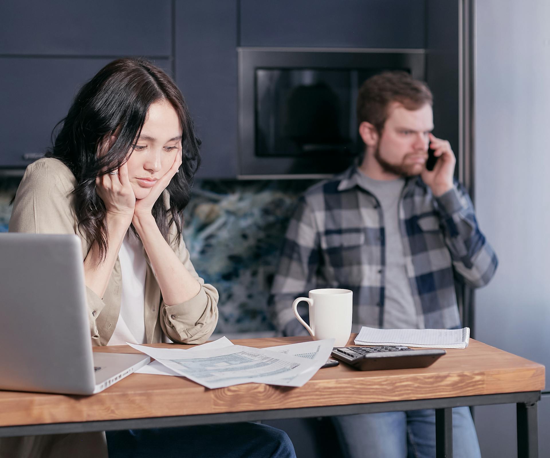 A Woman Sitting at a Desk Looking at Documents near a Man