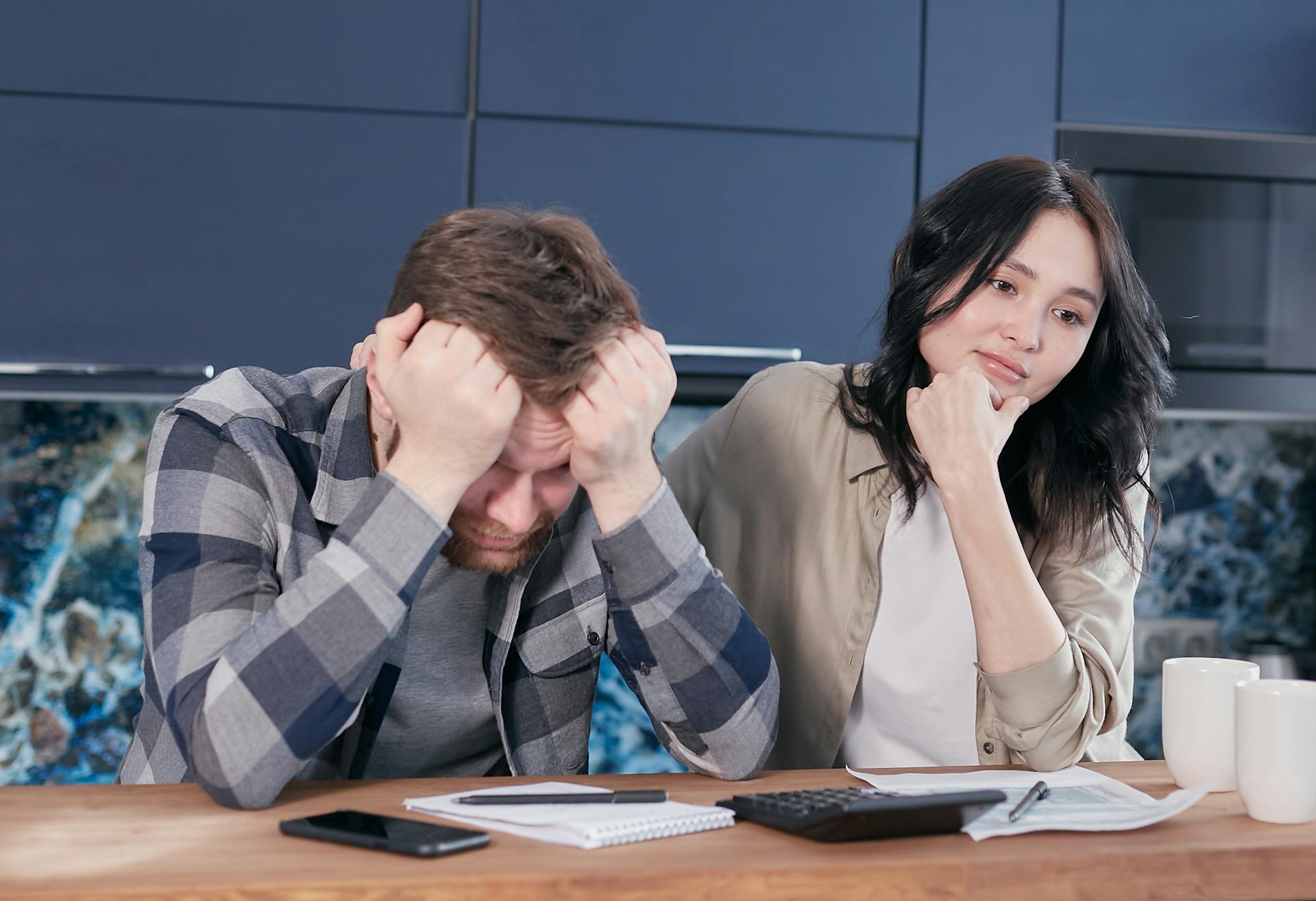 A Stressed Man Sitting at a Table Beside a Woman