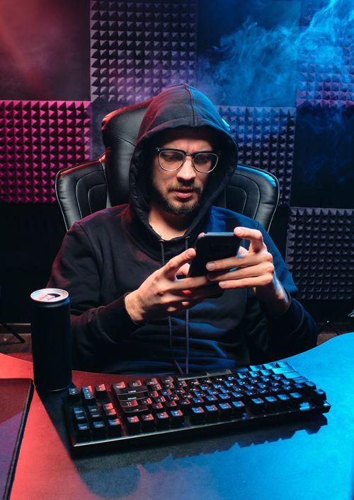 Free A seated tech-savvy adult using a smartphone in a gaming room. Stock Photo