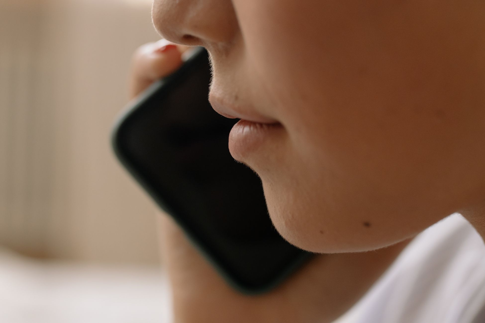 A close-up of someone talking on a smartphone, focusing on the lower face.