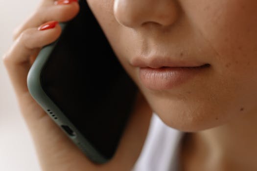 A close-up image of a woman holding a smartphone to her ear, emphasizing communication.