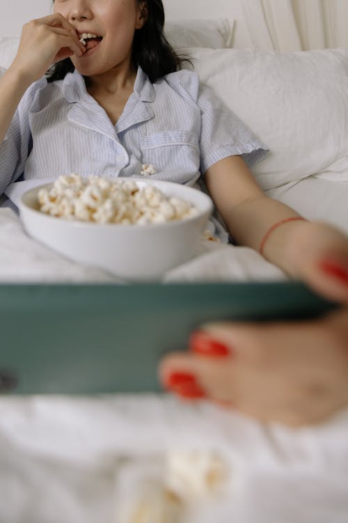 Free Woman Eats Popcorn in Bed Stock Photo