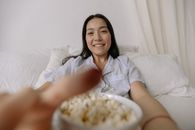 Smiling Woman in Bed with a Bowl of Popcorn