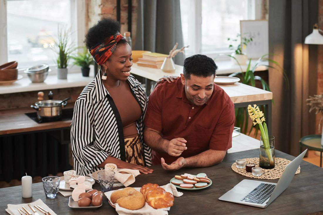 Couple Cooking And Looking At A Laptop