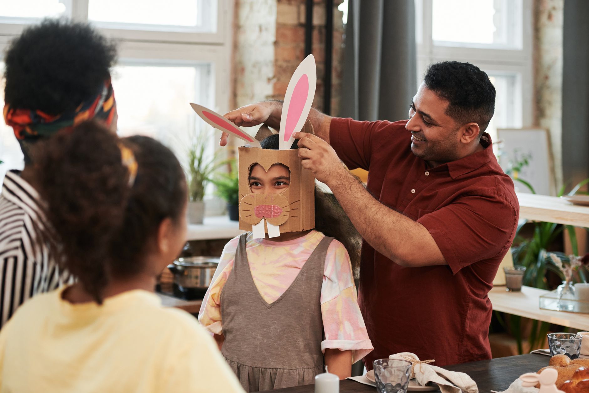 Family enjoying arts and crafts at home, making bunny costumes for Easter celebration.