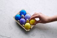 Person Holding Yellow Egg With Blue Egg