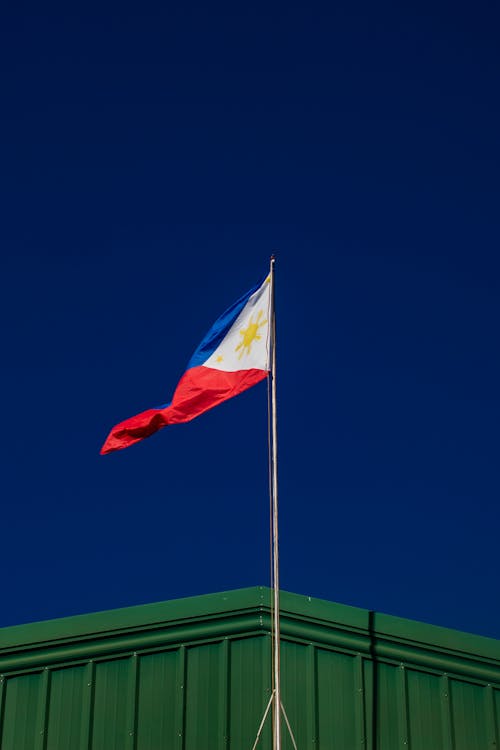 From below of national flag of Philippines placed on flagpole against cloudless blue sky