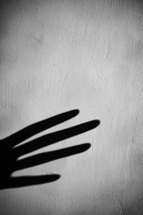 Shadow of crop hand on gray wall