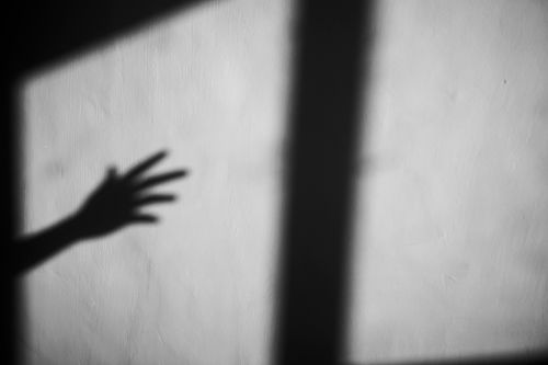 Free Shadow of crop arm with open fingers and window frame on shabby concrete gray wall Stock Photo