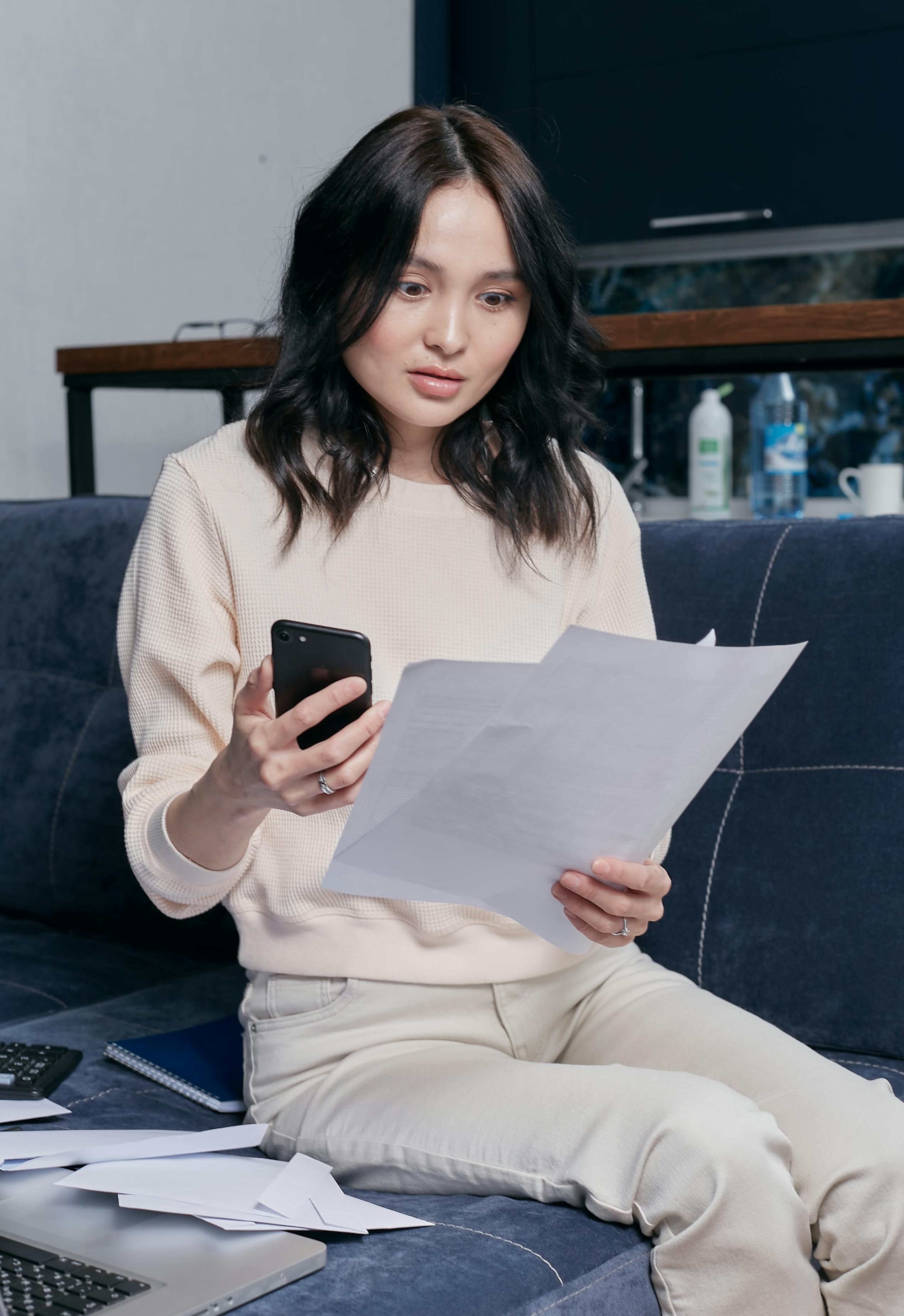 woman holding documents and smartphone