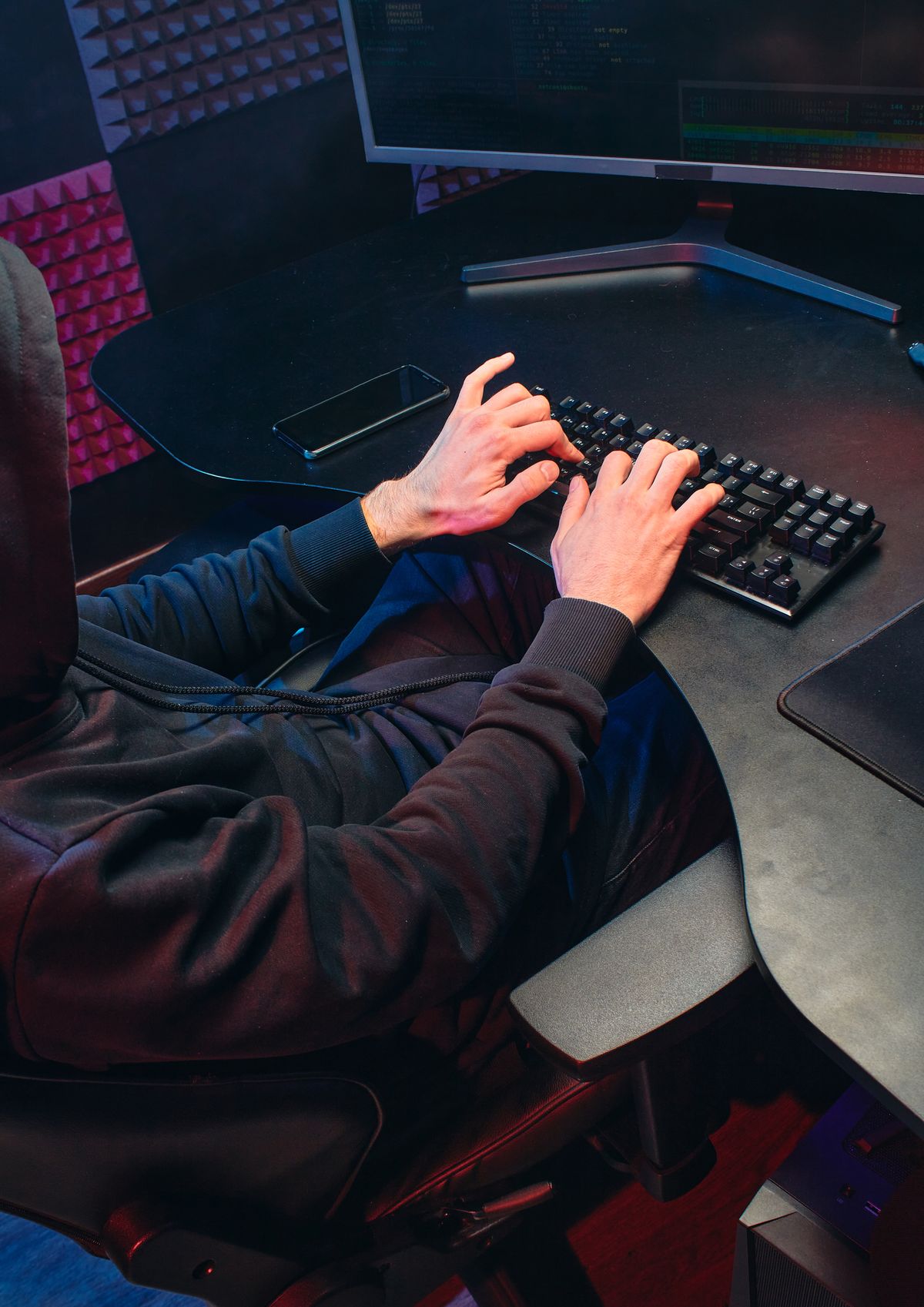 A silhouette of a person sitting in front of a glowing laptop screen in a dark room