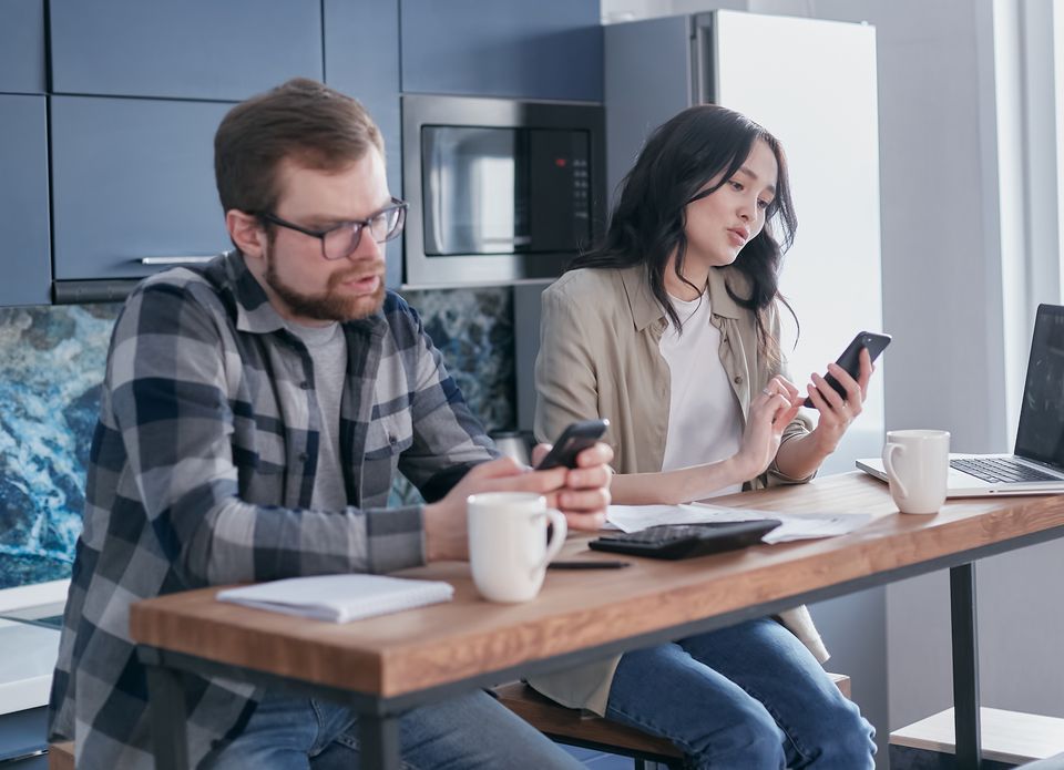二人でスマートフォンと資料を見ながら家計を確認する場面のイメージ。実際の利用者や銀行ではない