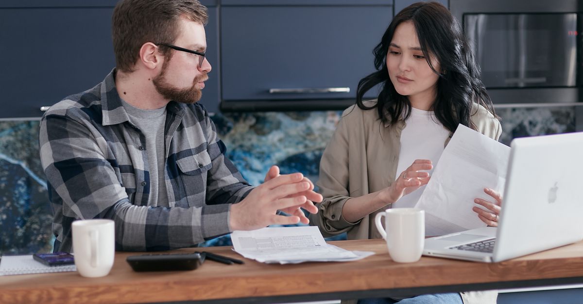 Young couple discussing financial issues with a laptop and documents in a modern kitchen.