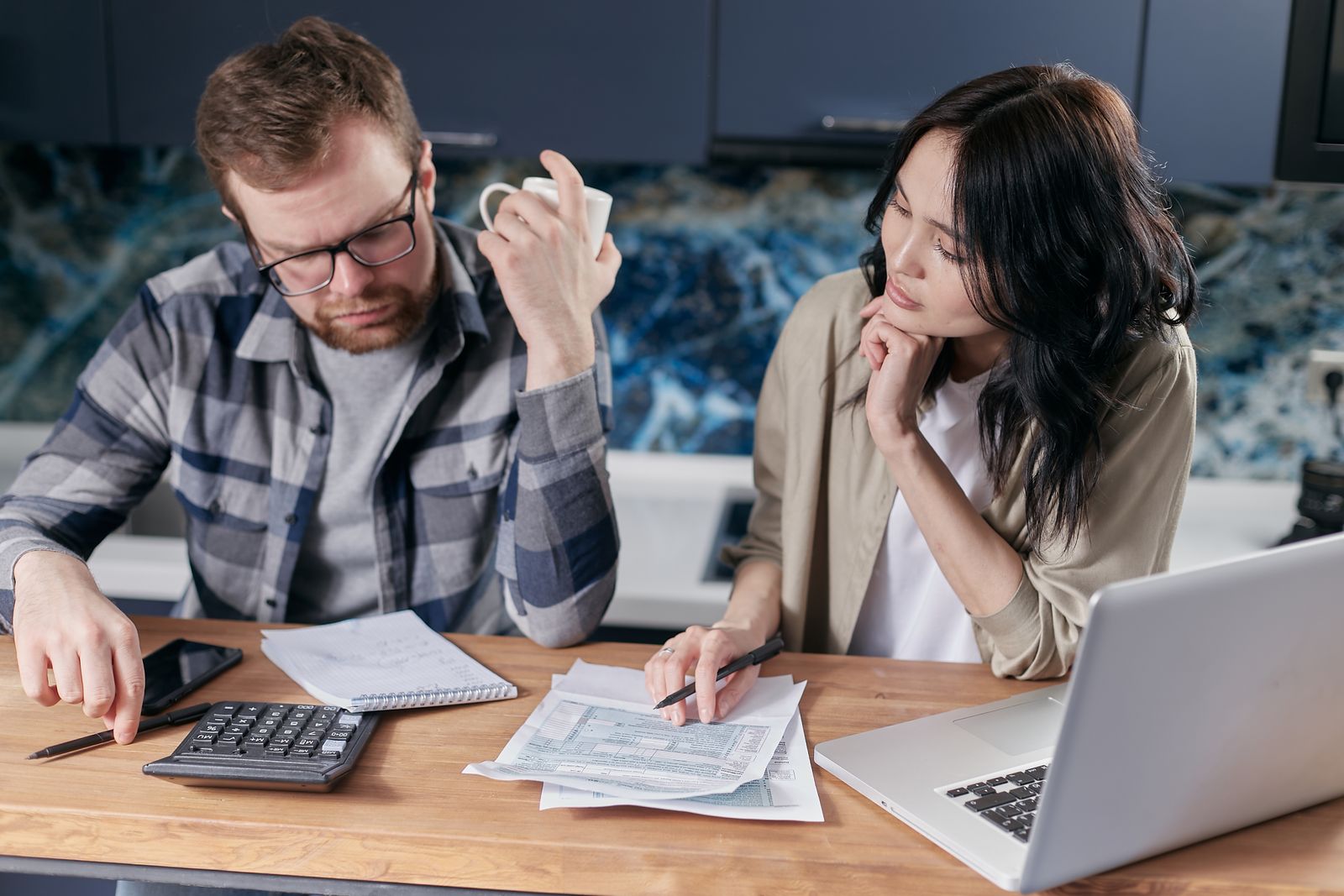 Free A couple reviews bills and documents on a laptop while discussing household finances. Stock Photo