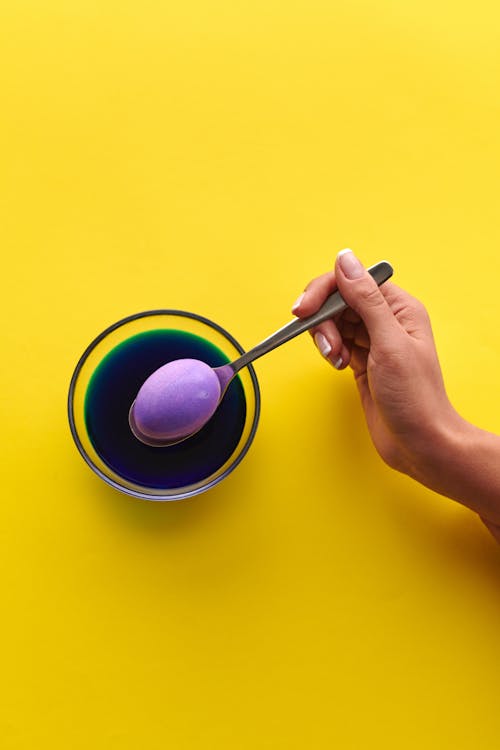 A Hand Holding a Spoon with Purple Egg