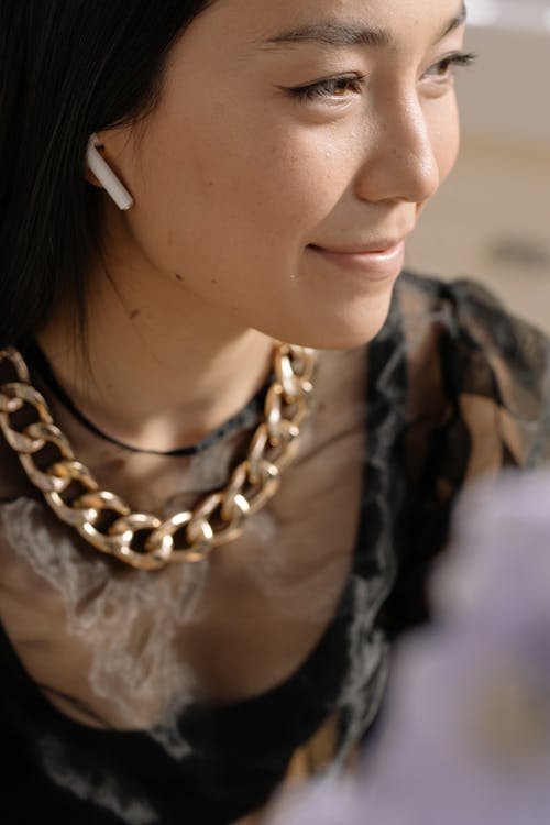 Woman in Gold Chain Necklace and Wireless Earphone