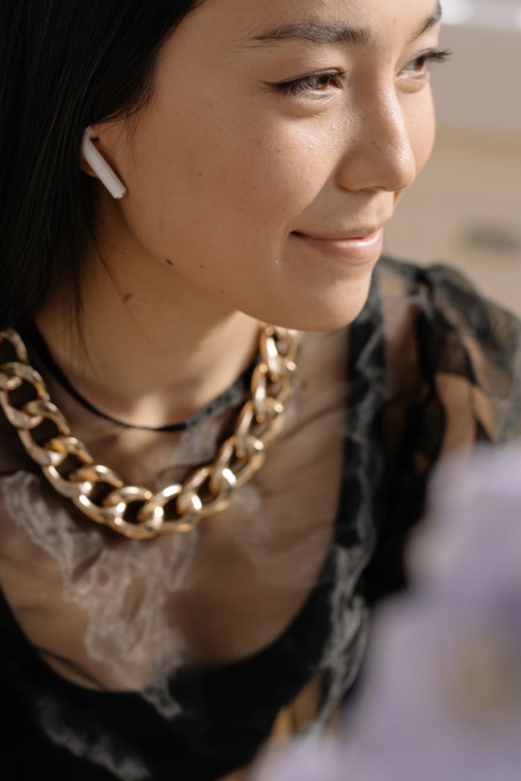 Woman In Gold Chain Necklace And Wireless Earphone