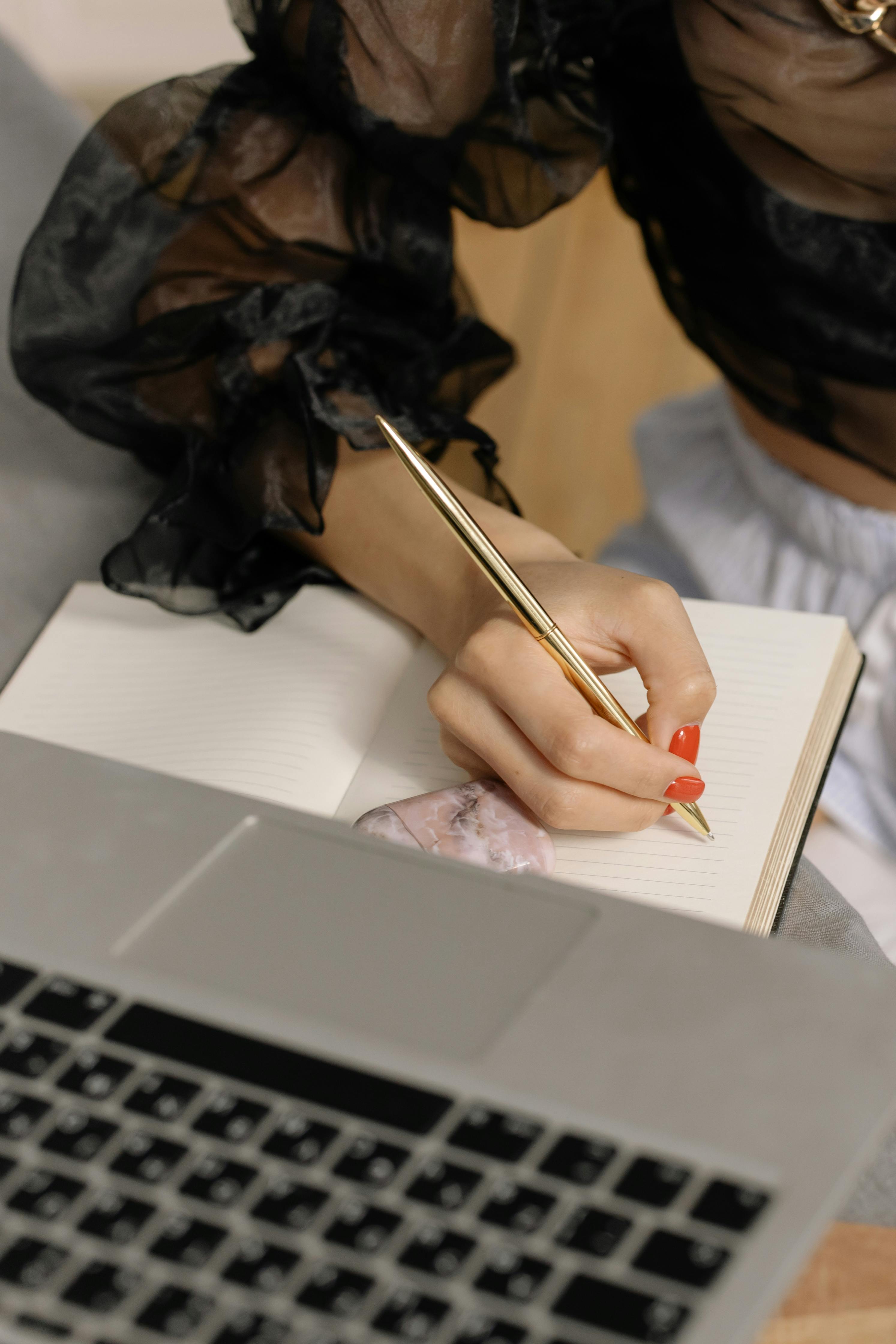 person holding a gold pen writing on notebook