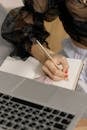 Person Holding a Gold Pen Writing on Notebook