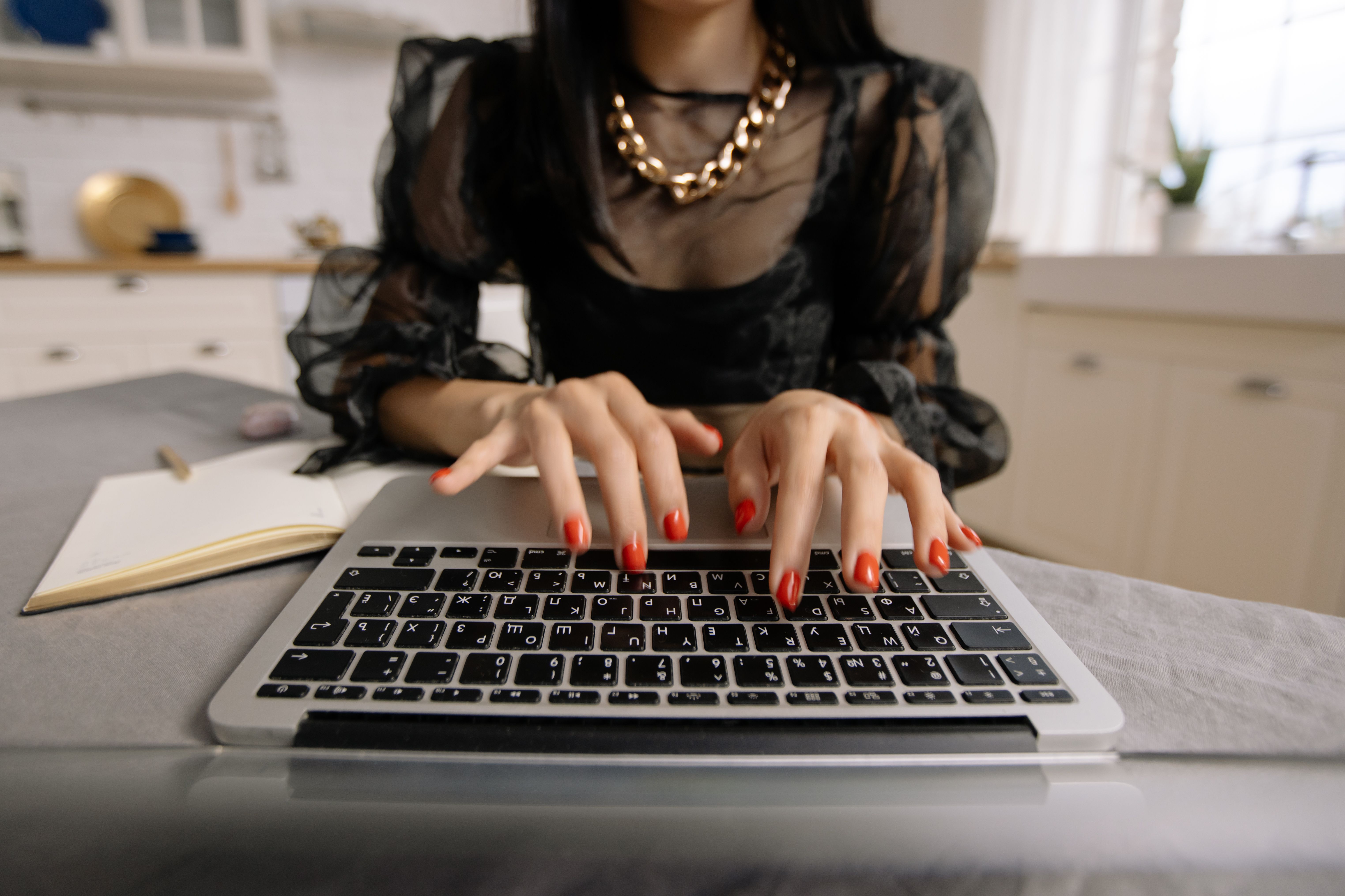Close-up of woman typing on a laptop in a home setting, ideal for remote work themes.