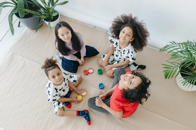 Top View Shot Of Kids Sitting On The Floor While Smiling At The Camera