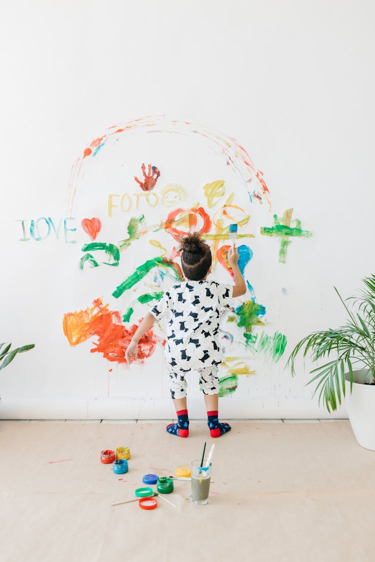 Back View Shot Of A Kid Painting The White Wall