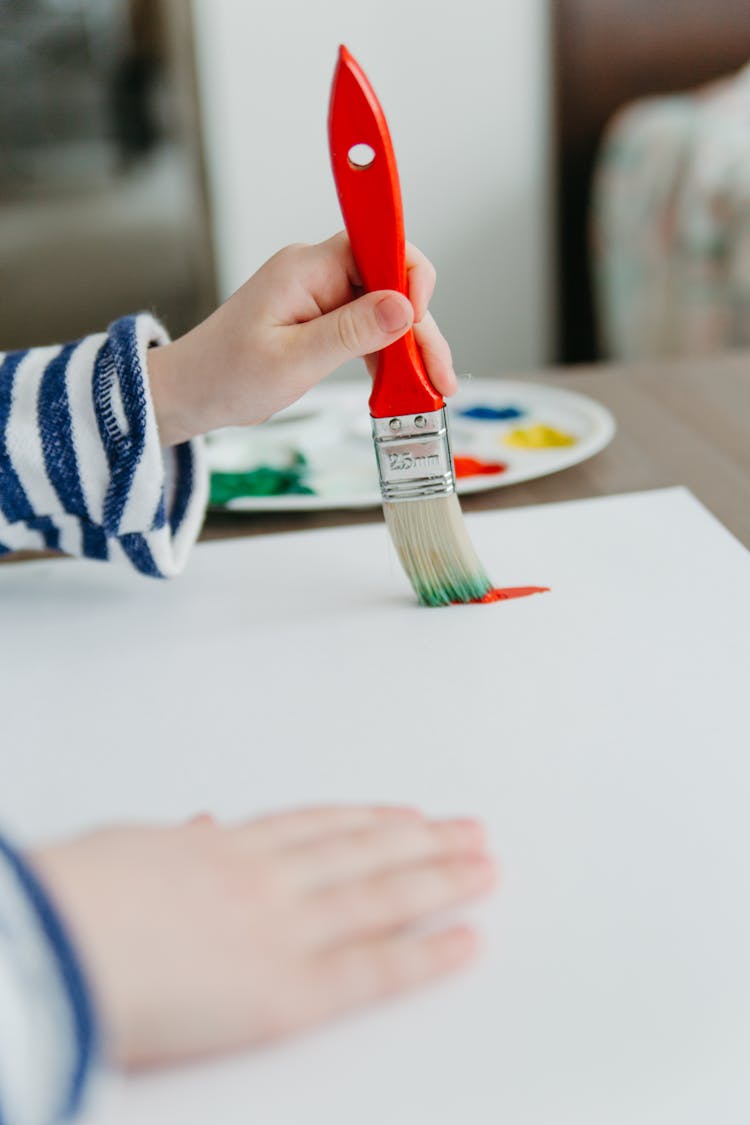 A Child Painting Using A Paintbrush