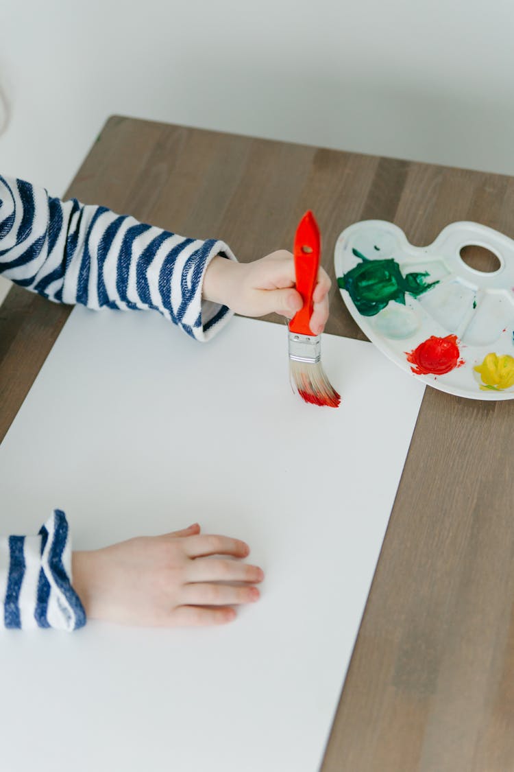 Child Painting A Canvas With Red Paint