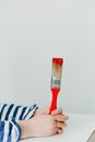 Child Holding a Paintbrush with Red Paint