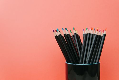 Free Vibrant colored pencils in a ceramic cup against a peach backdrop, offering creative inspiration. Stock Photo