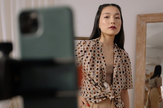 Confident woman posing for a selfie in a stylish outfit with a mirror in the background.