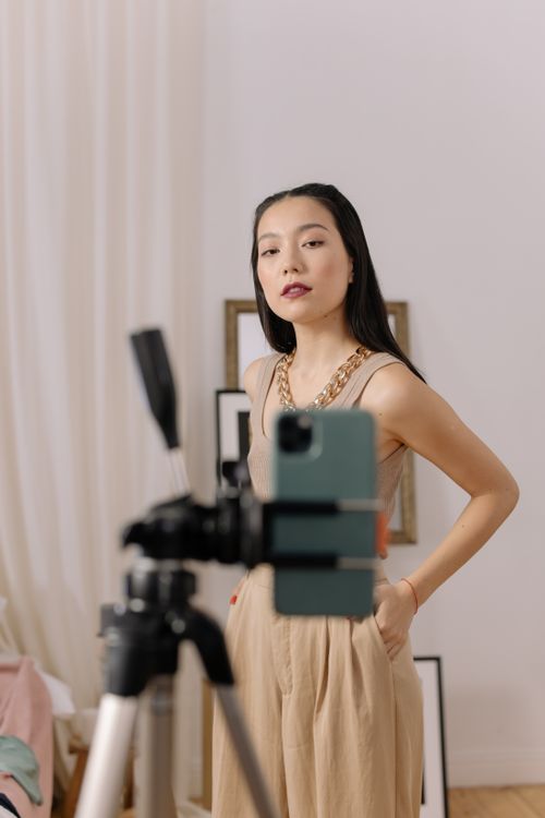 Free Stylish woman filming content with smartphone on tripod indoors. Stock Photo